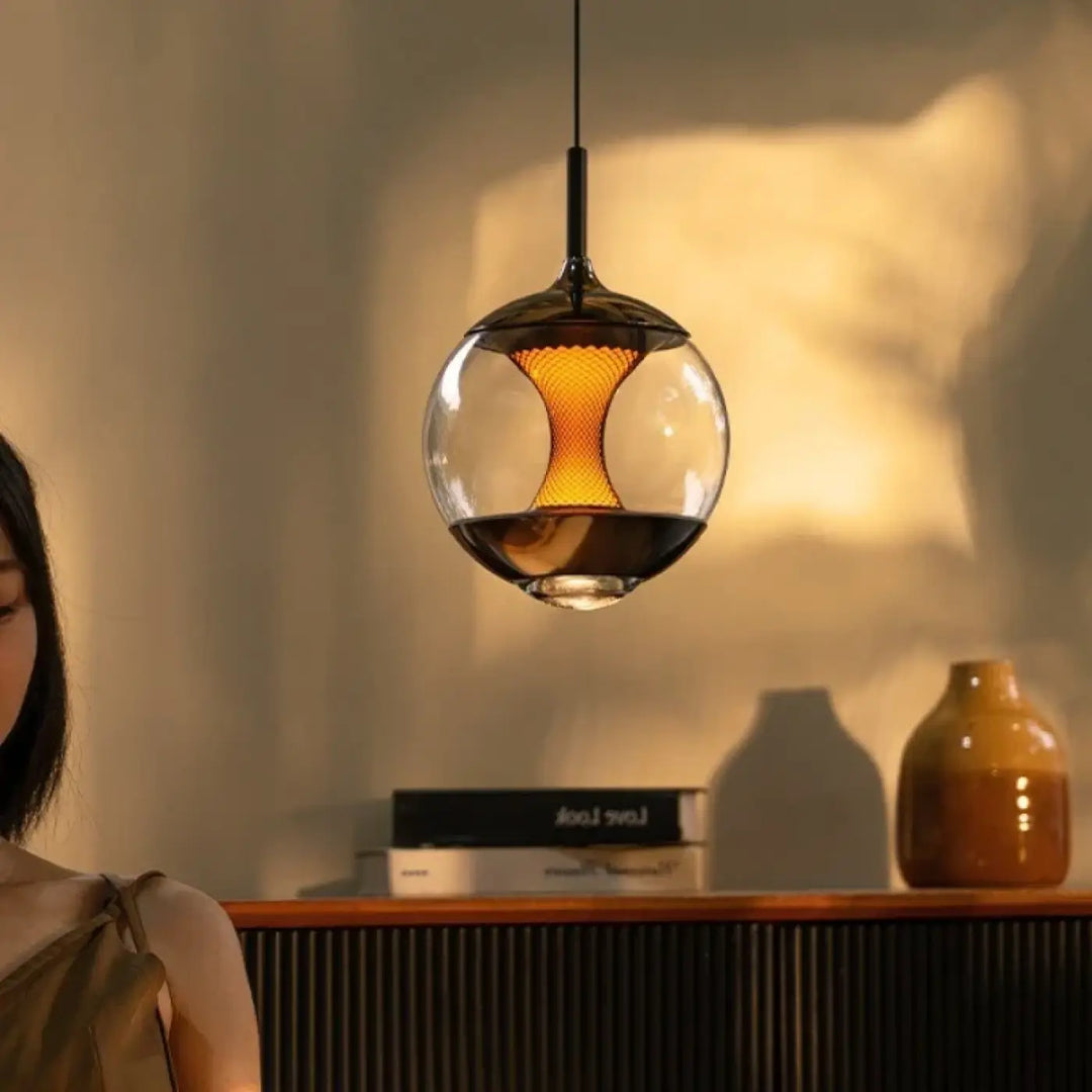 Suspension luminaire LUMA avec diffuseur central lumineux sphérique en verre transparent et intérieur en mesh orange éclairé