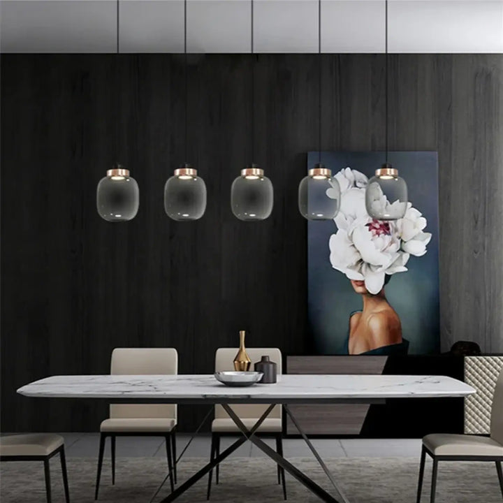 Suspension luminaire mistral avec cinq suspensions en verre gris fumé et accents en laiton au-dessus dune table en marbre