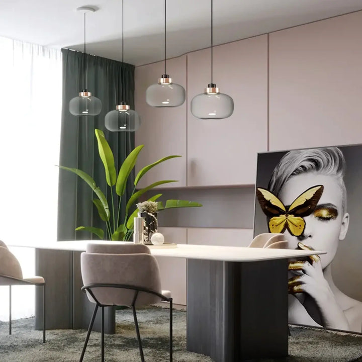 Suspension luminaire mistral avec verre gris fumé et accents métalliques suspendue au-dessus d’une table à manger