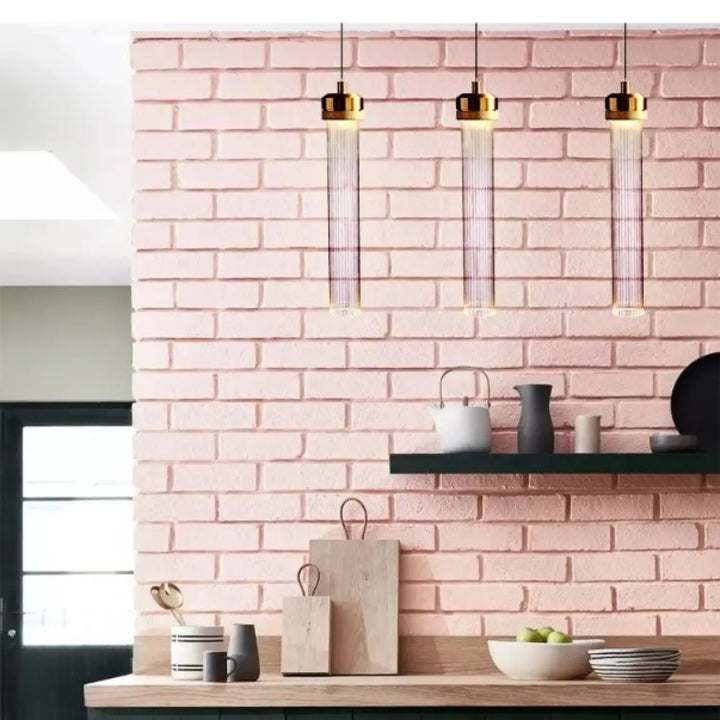 Trois suspension luminaires vibris élégants finition or avec tubes en verre verticaux suspendus au-dessus du comptoir