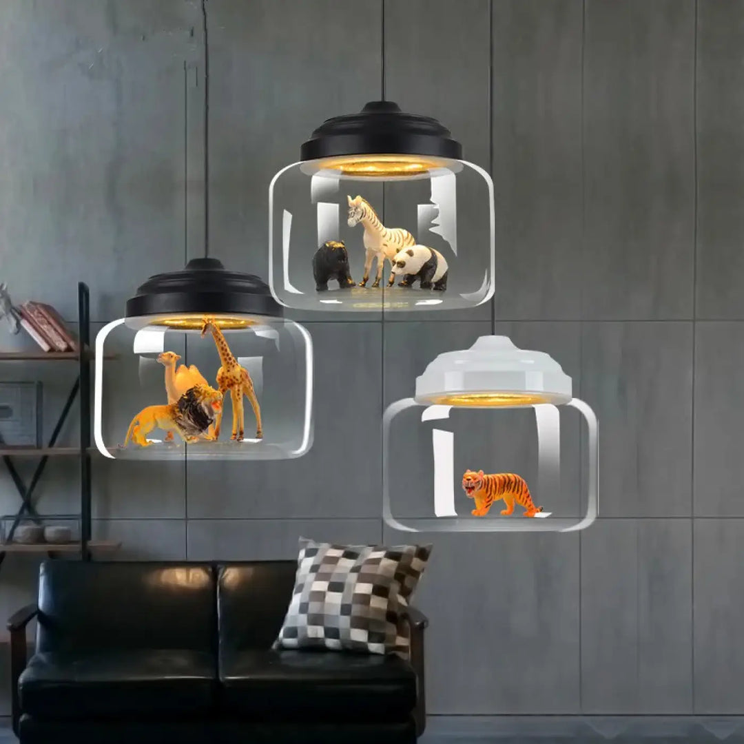 Suspension luminaire savon en verre transparent avec couvercles noirs et blancs contenant des animaux sauvages miniatures