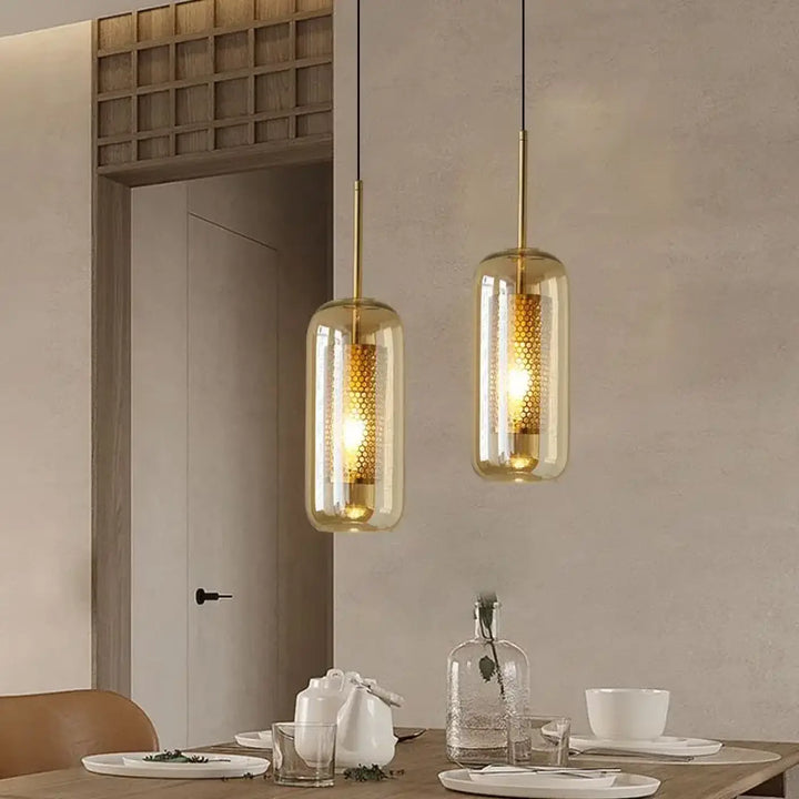Suspension luminaire eloria avec deux pendentifs dorés et verre transparent aux nuances ambrées en motif nid dabeille