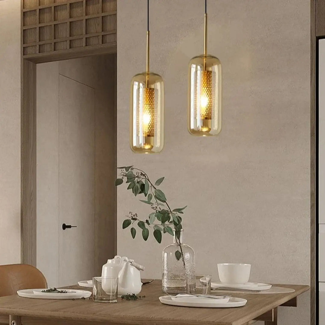 Suspension luminaire eloria avec verre transparent aux motifs alvéolés dorés au-dessus d’une table en bois