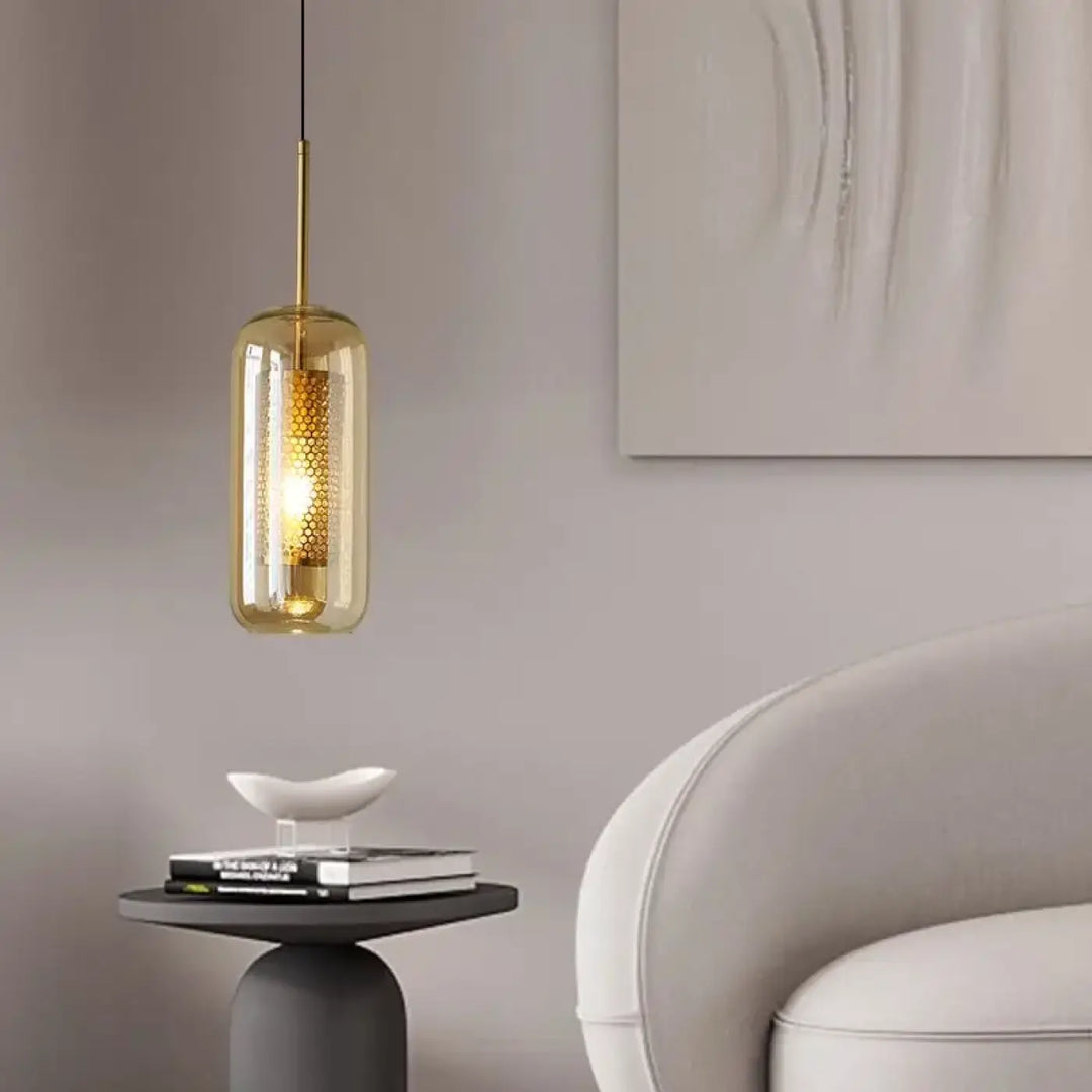 Suspension luminaire eloria en verre transparent aux teintes ambre avec cadre métallique doré et motif alvéolé