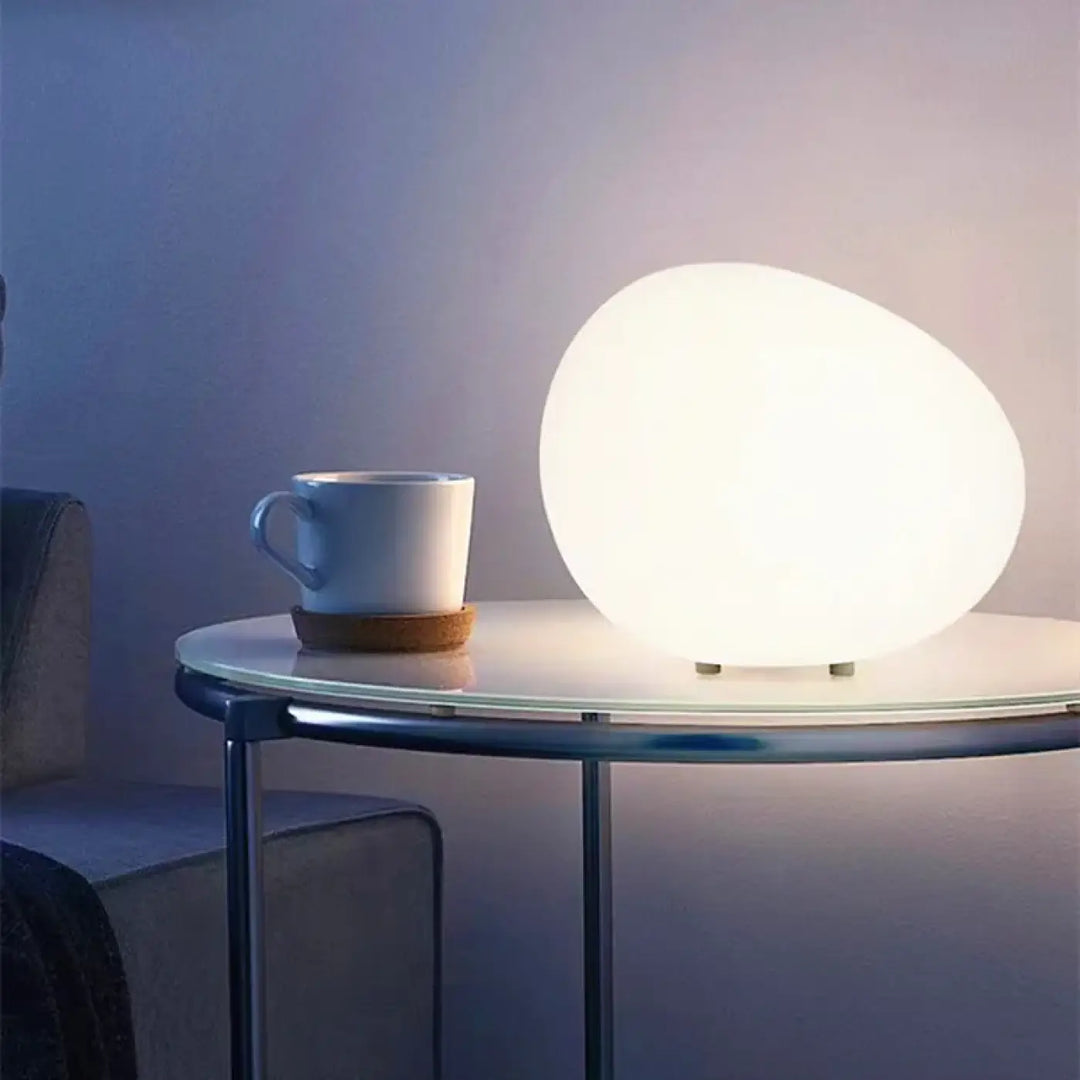 Veilleuse contemporaine inspirée d’un galet avec une surface translucide blanche et un éclairage doux en forme ovoïde