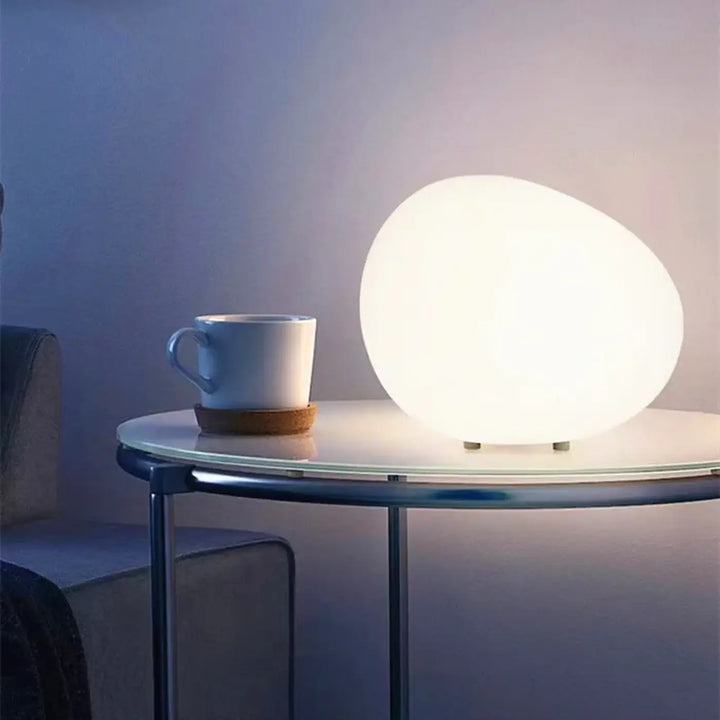 Veilleuse contemporaine inspirée d’un galet avec une surface translucide blanche et un éclairage doux en forme ovoïde