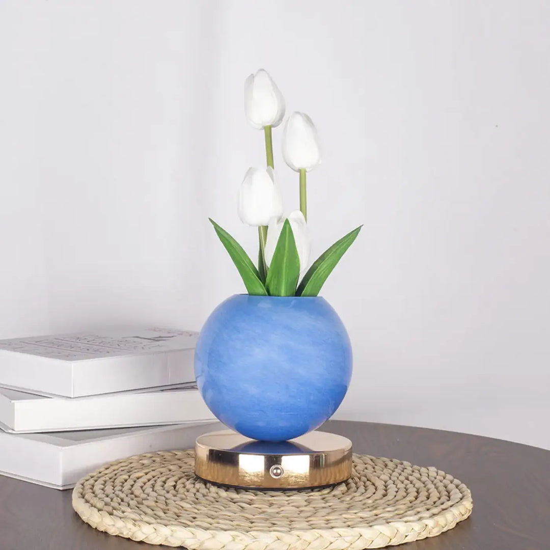 Lampe de table tulyna avec vase en céramique bleu sphérique, tulipes blanches, feuilles vertes, base magnétique dorée comme source lumineuse