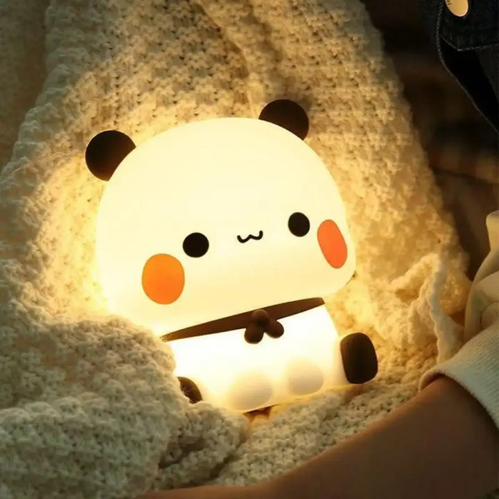 Veilleuse panpan en forme de panda blanc avec oreilles noires joues orange et ceinture marron offrant une lumière douce chez soi